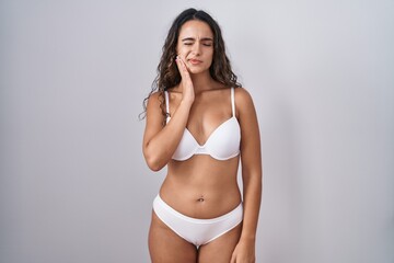 Young hispanic woman wearing white lingerie touching mouth with hand with painful expression because of toothache or dental illness on teeth. dentist