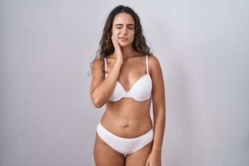 Young hispanic woman wearing white lingerie touching mouth with hand with painful expression...