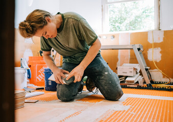 Woman mason works with tile on a bathroom remodel and renovation for home improvement needs