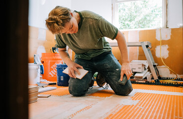Woman mason works with tile on a bathroom remodel and renovation for home improvements needs