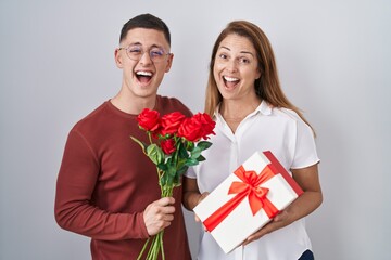 Mother and son holding mothers day gift smiling and laughing hard out loud because funny crazy joke.