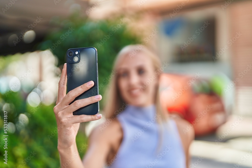 Sticker Young blonde woman smiling confident making selfie by the smartphone at street