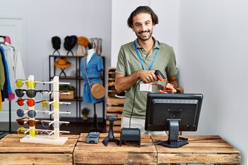 Handsome hispanic man working at shop using barcode scanner at retail shop