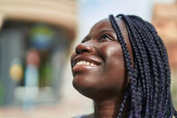 African american woman smiling confident looking to the sky at street