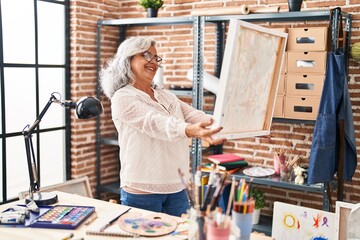 Middle age woman artist smiling confident looking draw at art studio