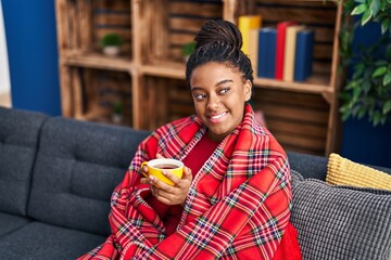 African american woman drinking coffee sitting on sofa at home