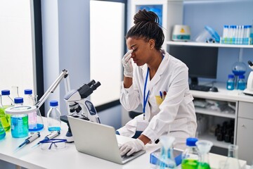 African american woman scientist stressed using laptop working at laboratory