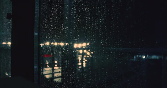 Rain drops on window glass in heavy rain with lightning in night