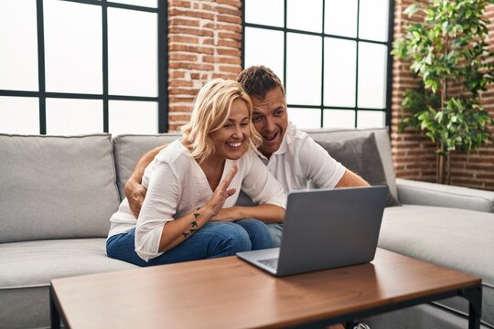 Middle age man and woman having video call sitting on sofa at home