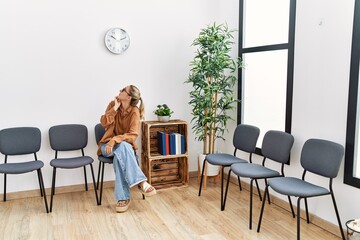 Young blonde woman with serious expression at waiting room