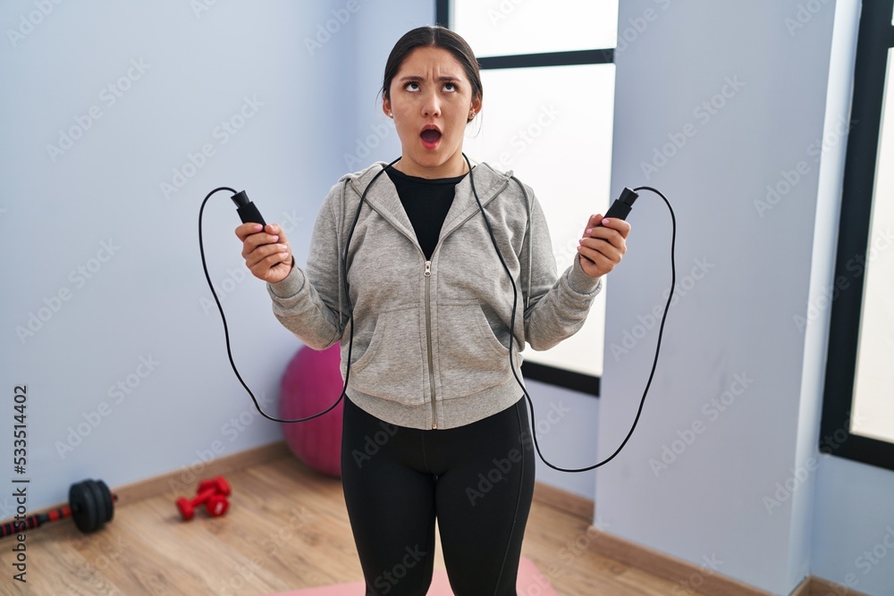 Canvas Prints Young latin woman jumping with skipping rope angry and mad screaming frustrated and furious, shouting with anger looking up.