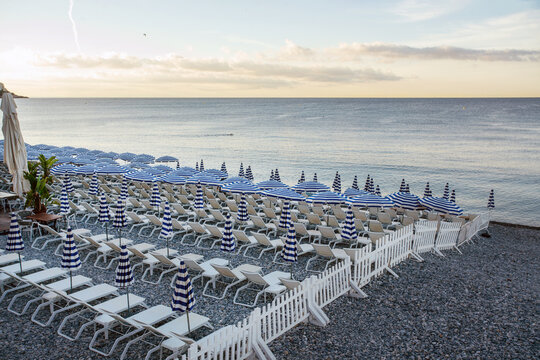 Good morning in Nice  with part of private beach with beach chairs and umbrellas . At far distance perspon swimming