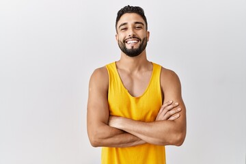 Young handsome man with beard standing over isolated background happy face smiling with crossed...