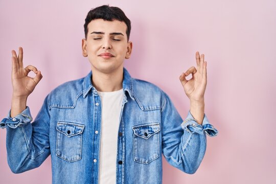 Non binary person standing over pink background relax and smiling with eyes closed doing meditation gesture with fingers. yoga concept.
