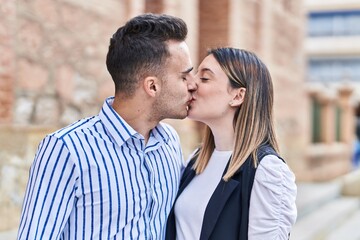 Man and woman couple hugging each other kissing at street