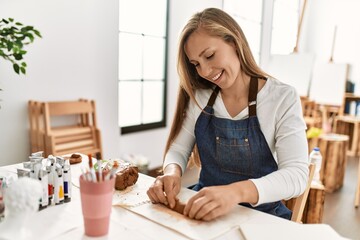 Obraz na płótnie Canvas Young caucasian woman smiling confident make handmade clay pot at art studio
