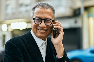 Middle age southeast asian man smiling speaking on the phone at the city