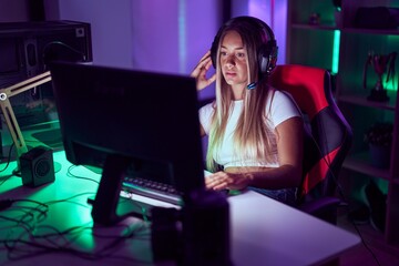 Young beautiful hispanic woman streamer playing video game with serious expression at gaming room © Krakenimages.com