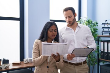 Man and woman business workers reading document standing together at office