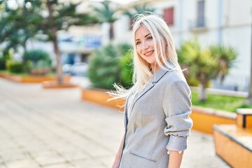 Young blonde woman smiling confident standing at park