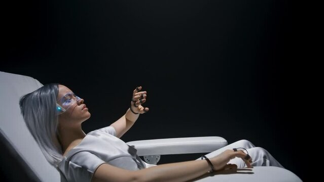 Woman having VR experience zoom on. Girl using sensor gloves sitting armchair