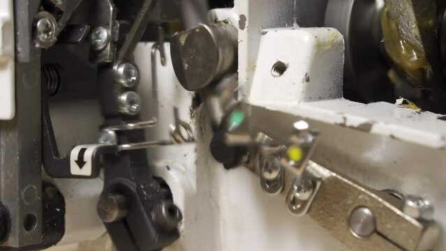Mechanism of sewing equipment. Close-up. Repair of overlock and sewing machines. Mechanism at work