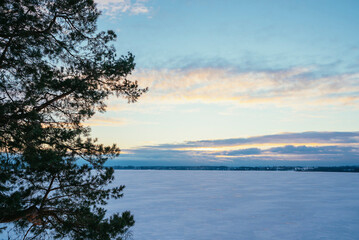 landscape at sunset frozen lake covered with snow in winter on a cold day