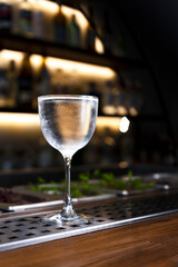 A misted glass of refreshing alcoholic drink on a bar counter. Bar background. Vertical...