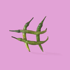 Four green peppers making a hashtag on pink background. Minimal concept for digital era banner or...