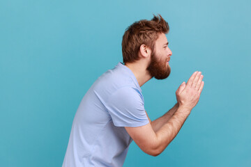 Please, I'm begging. Side view of bearded man holding arms in prayer, asking help or forgiveness...