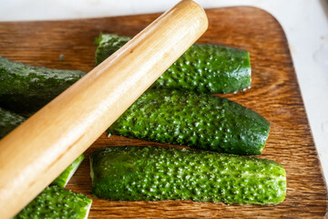 Preparation of beaten cucumbers. Halves of fresh cucumbers on a cutting board.