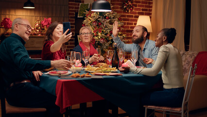 Beautiful woman presenting Christmas dinner to friend through smartphone internet video call. Festive family on cellphone online call with relatives wishing them Happy Holidays.