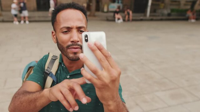 Close up, young man tourist takes photo on cellphone while standing on the square of the old city