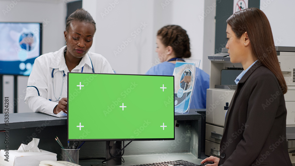 Poster diverse medical team using computer with greenscreen at reception counter. facility staff working wi