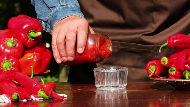 Delicious homemade vegetarian sauce with a sweet bell peppers and hot pepper chilli. Ketchup pouring from a sauceboat in glass bottle. Cooking tasty lecho, slow motion