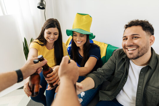 Host bringing beers to group of friends watching a football match on TV