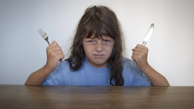 Shout for food in crisis. A hungry child with knife and fock shout for food in the empty kitchen. A concept of food crisis in the world.