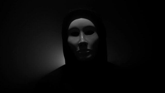 Man wearing mask with hoodie on black background.