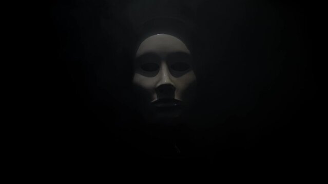 Man wearing mask with hoodie on black background.