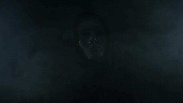 Man wearing mask with hoodie on black background.