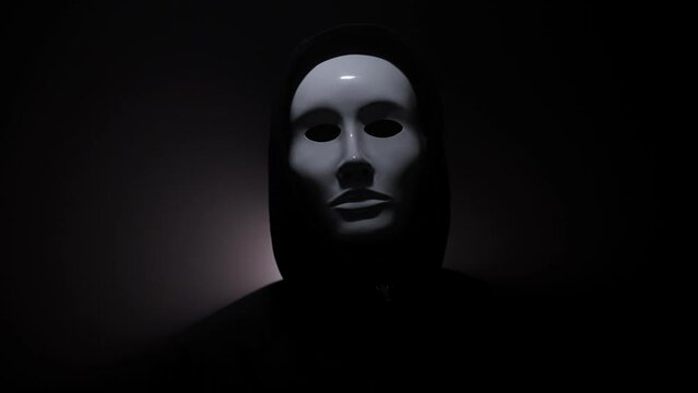 Man wearing mask with hoodie on black background.