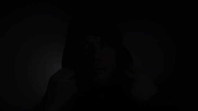 Handsome man puts on black hoodie.
