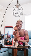 Transgender beauty content creator applying makeup to mobile phone camera