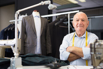 Portrait of an accomplished positive tailor with crossed arms in his workshop