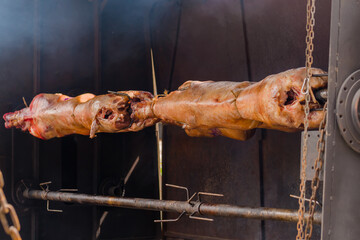Process of cooking roasted whole ram carcasses on spit at summer outdoor food festival, market: close up. Professional cooking, cookery, preparation, gastronomy and street food concept - obrazy, fototapety, plakaty