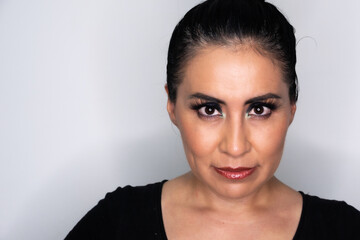 Close up of a serious and staring Latin Mexican woman with long eyelashes and black eyes on white background
