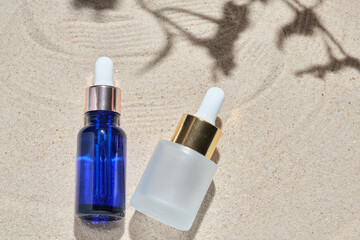 face serum of glass bottle with a pipette on a natural background with sand. Essential oil for moisturizing body skin. mockup of beauty fashion cosmetic bottle dropper product with skincare concept.