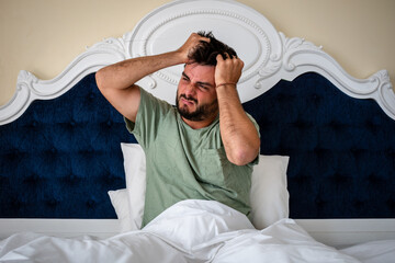 Hombre levantandose de la cama con malestar, resaca y dolor de cabeza