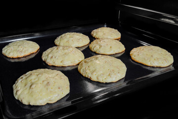 Process of cooking eight homemade crunchy oatmeal cookies on metal sheet in oven. Dessert, cookery,...