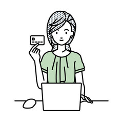 デスクで座ってPCを使いながらクレジットカードを手に持っているオフィスカジュアルの女性